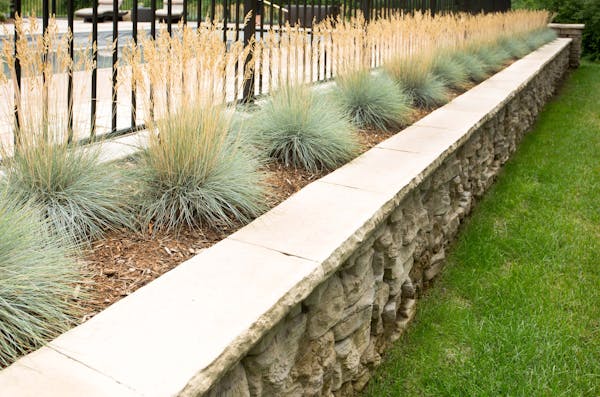 Concrete retaining wall with landscaping and a fence