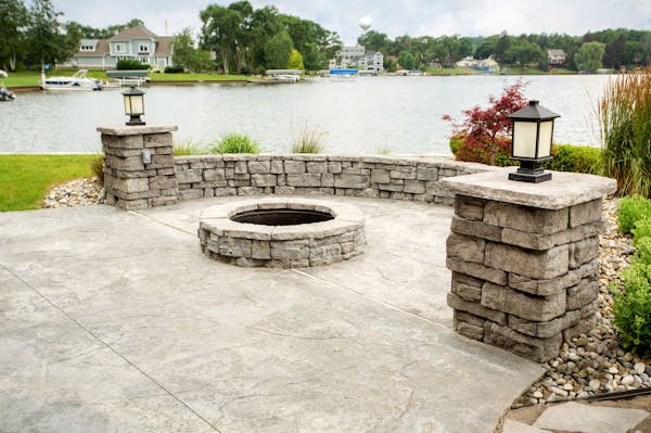 Freestanding seat walls surround a fireplace with a lake view
