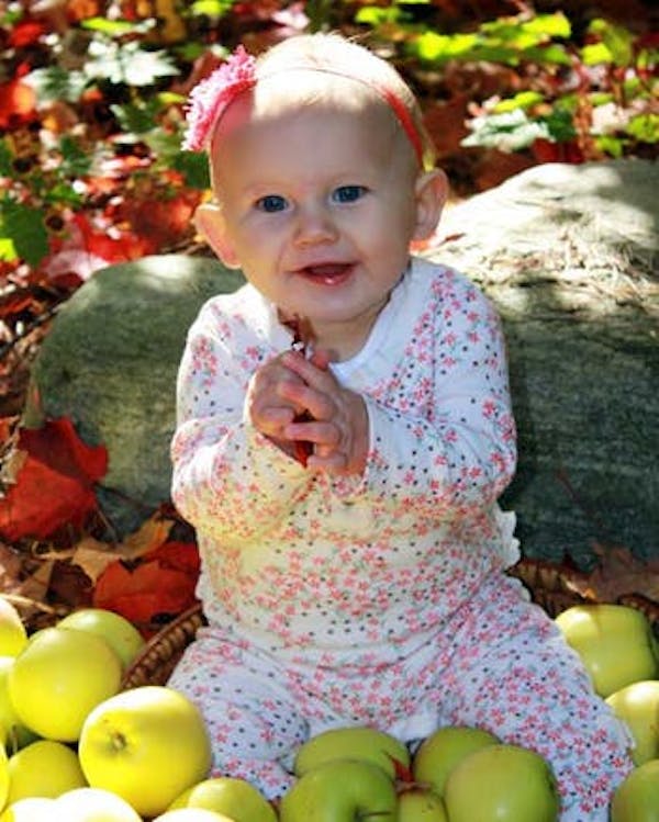 Baby sitting in bushel of apples