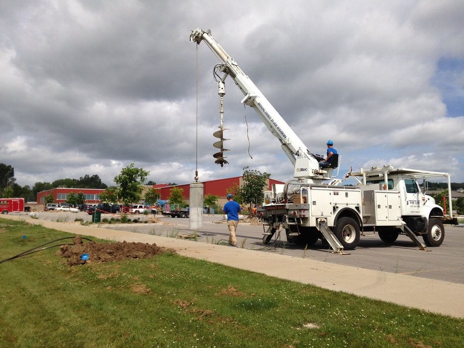 Installing precast light pole bases with an auger