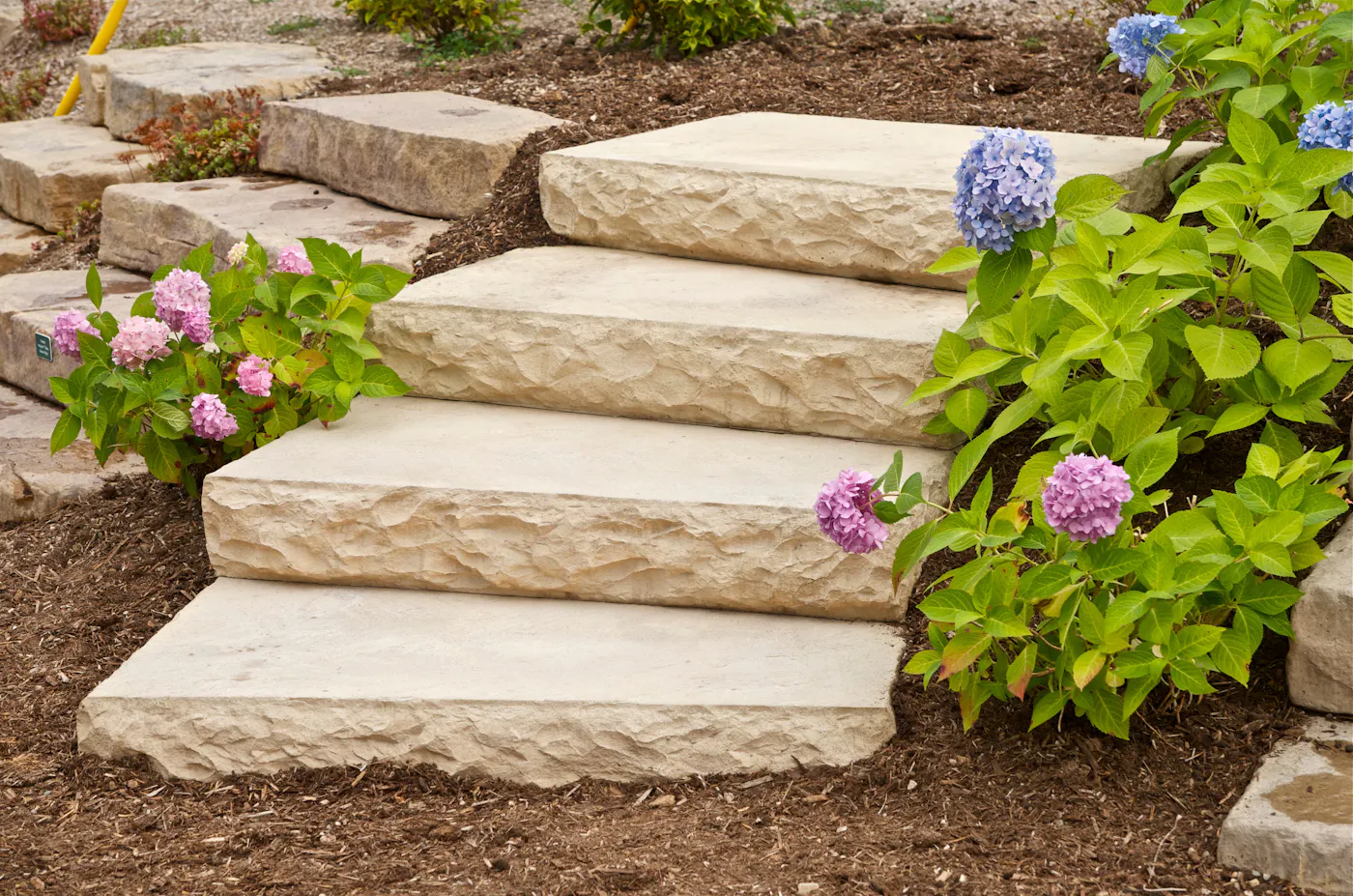 Dimensional Step staircase among a mulched garden of flowers