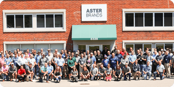 group photo of about fifty people in front of Aster Brands building 