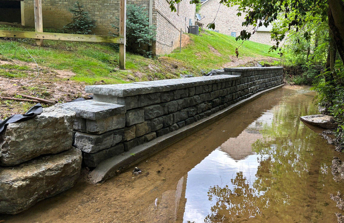 image of ridge textured novum wall next to stream and buildings in background