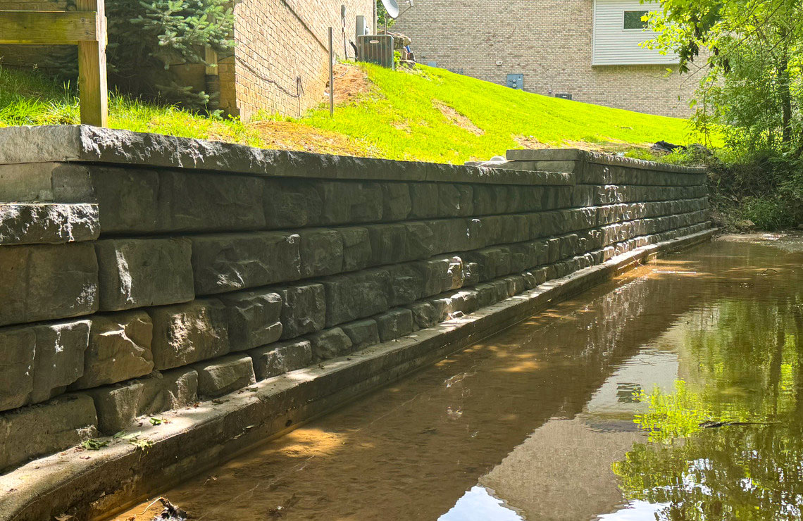 image of ridge textured novum wall next to stream and buildings in background