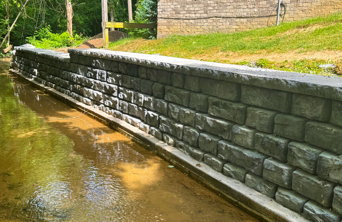 image of ridge textured novum wall next to stream and buildings in background