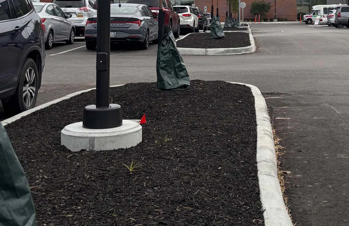 A partially embedded Pole Base light pole foundation is completely installed in a parking lot application.