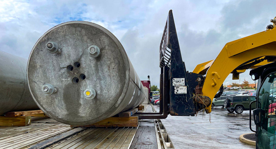 image of pole base being lifted by excavator from truck bed