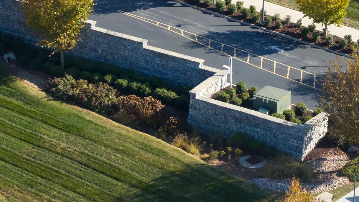 A aerial view of a tall Redi-Rock block retaining wall, finished with cap blocks. 
