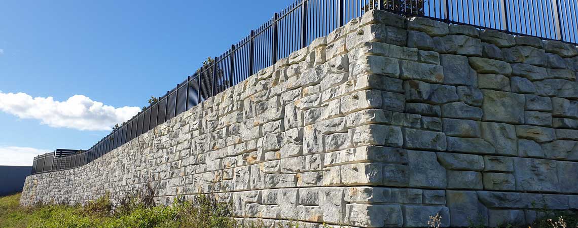 image of corner of redi-rock ledgestone retaining wall with fence on top