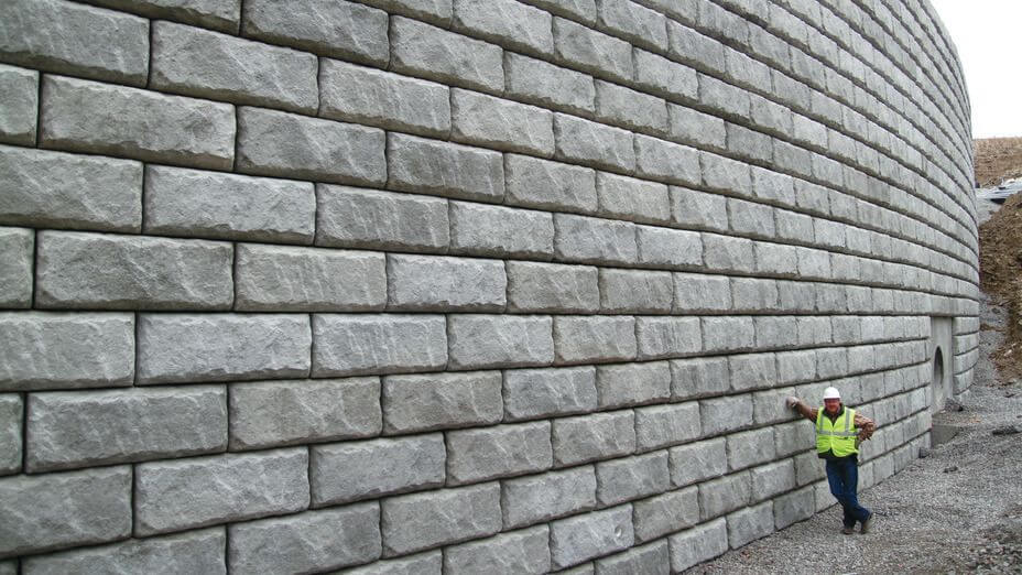 Man leaning against 41 foot tall Limestone retaining wall