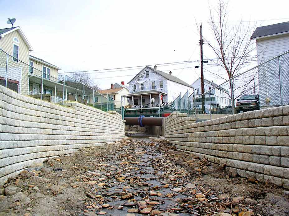 RCobblestone flood walls with fencing line the Coal Creek storm channel