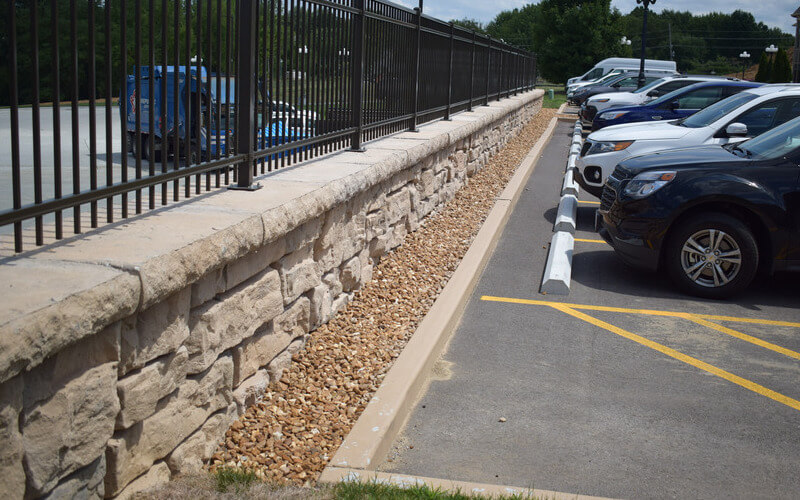 image of redi-rock freestanding hollow core blocks used for parking lot with fence on top of wall