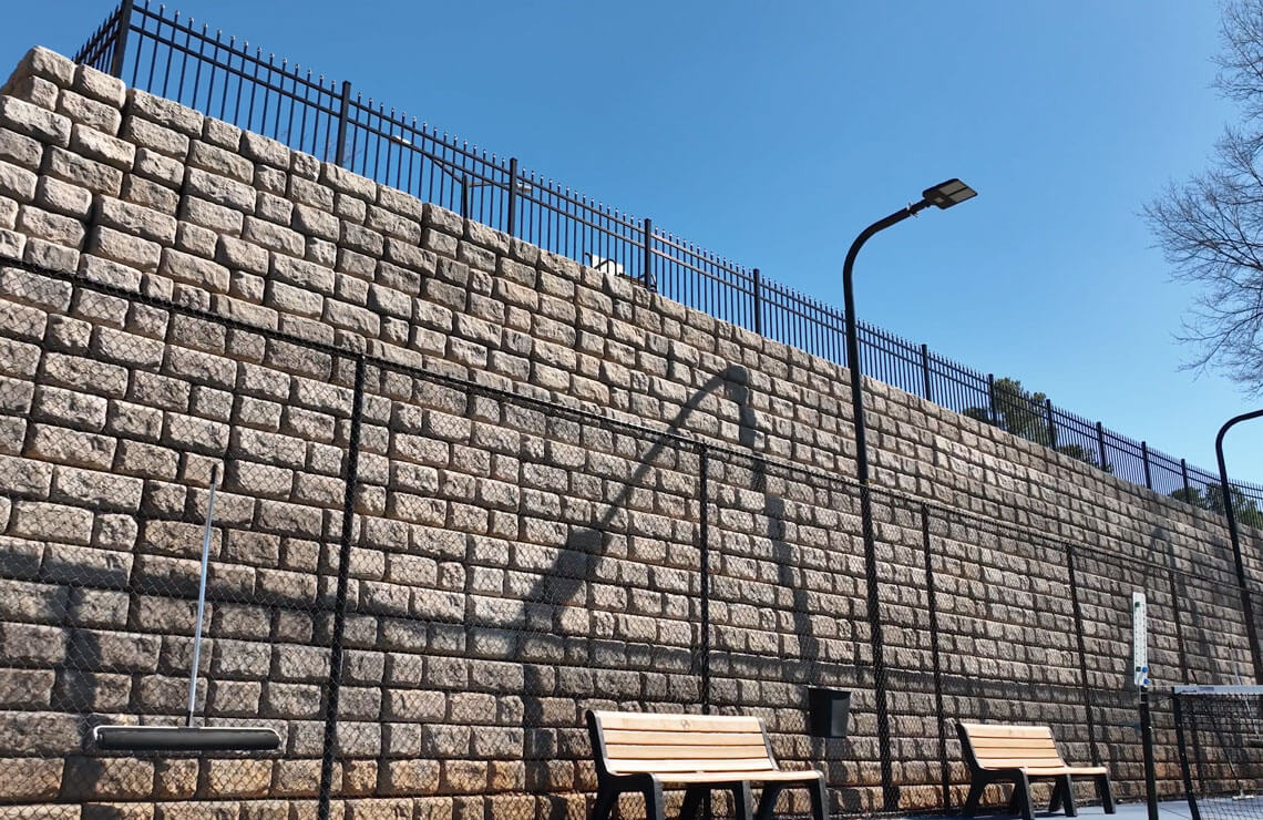image of redi-rock XL wall with fence and benches and light pole in front of wall