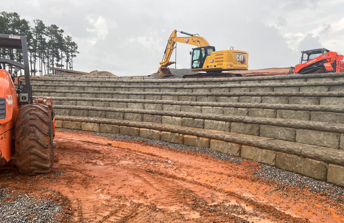 image of excavators installing redi-rock blocks for amphitheater 