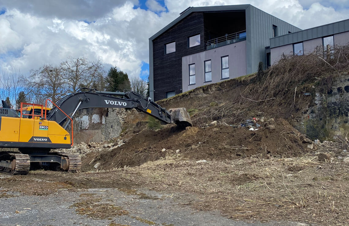 image of excavator digging out unstable dirt in front of building