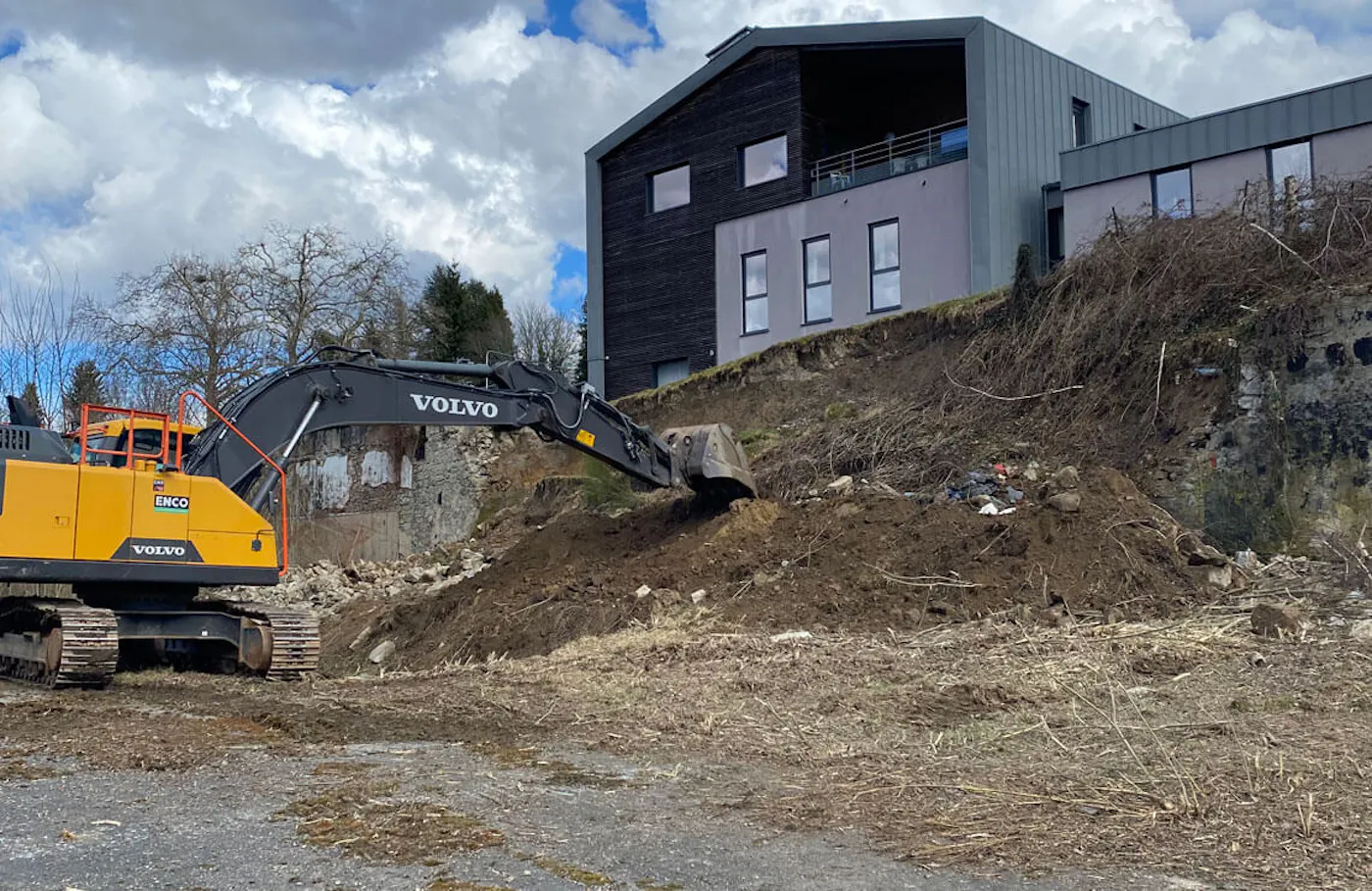 image of excavator digging out unstable dirt in front of building