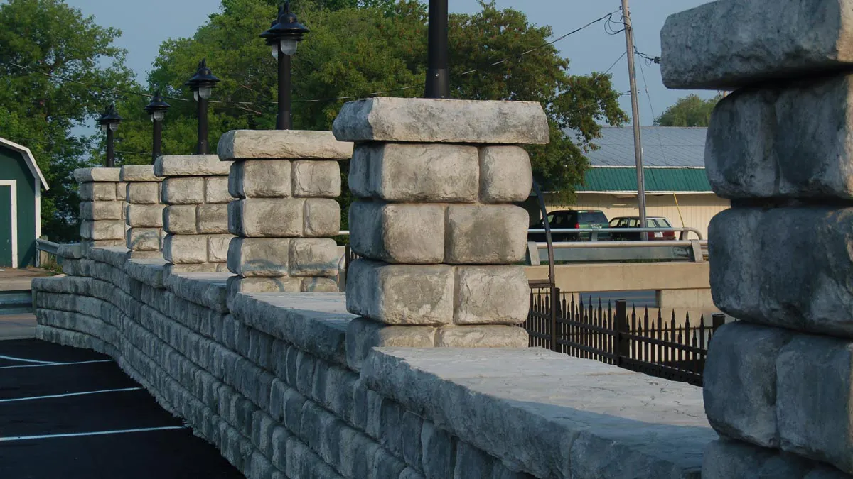 Redi-Rock Cobblestone gravity wall blocks create a barrier wall in a parking lot with lighted columns. 