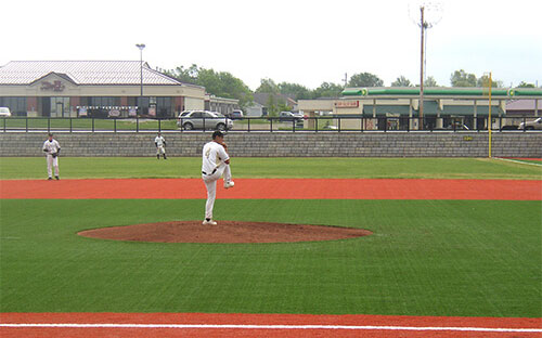 baseball field with pitcher about to pitch with redi-rock wall in background