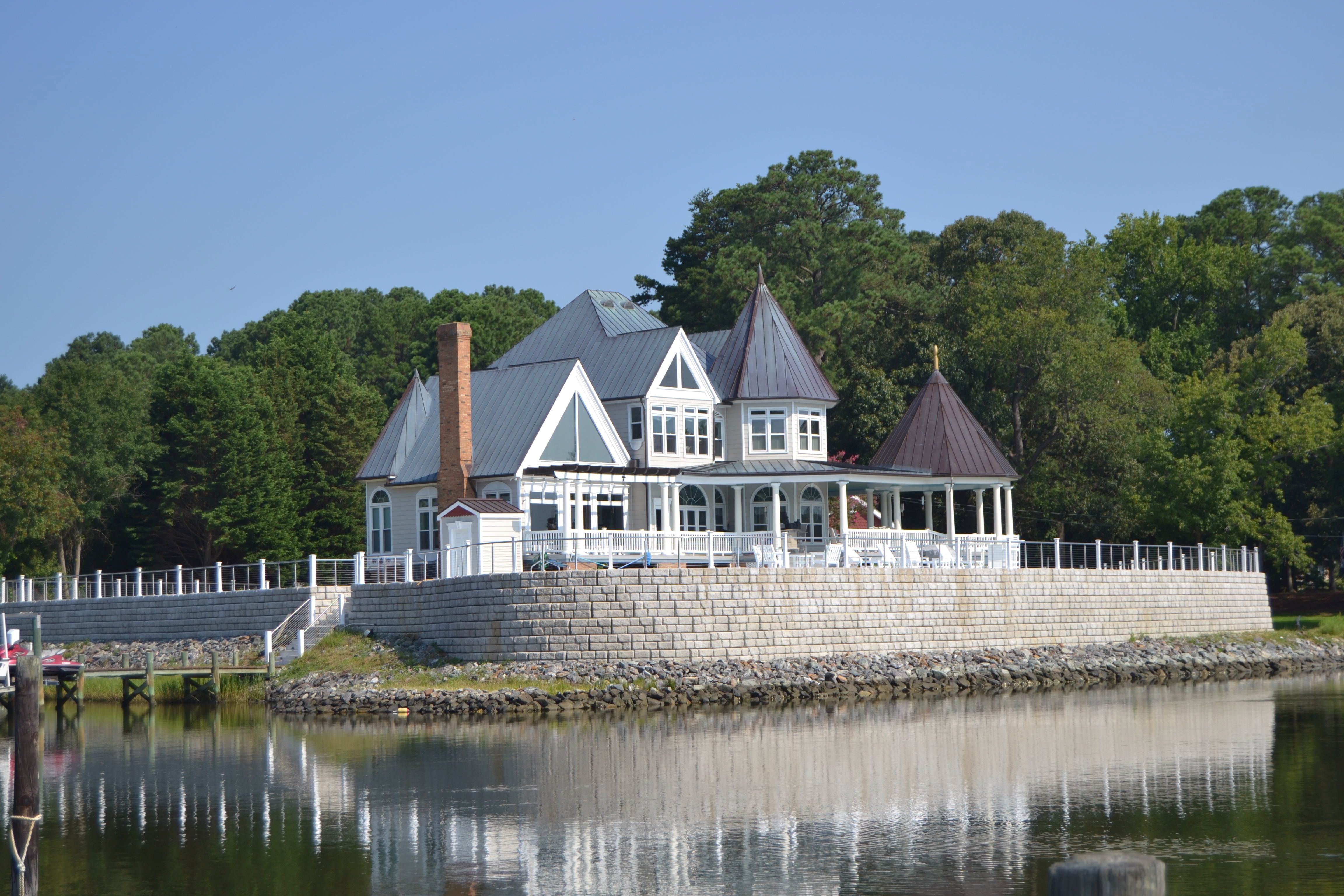 Redi-Rock Cobblestone wall with white victorian home on lakeside