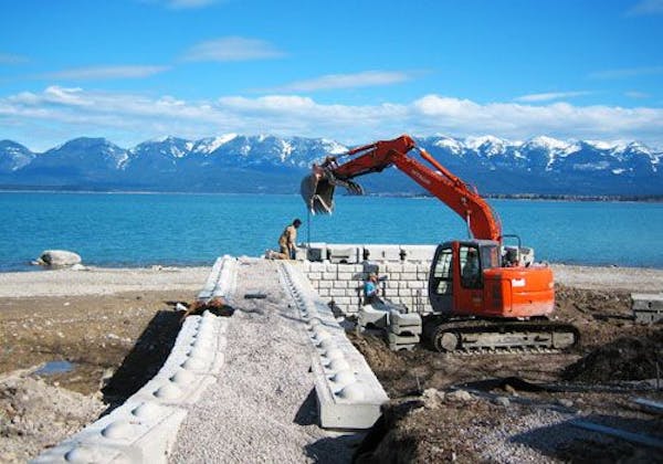 A crew installs Redi-Rock in a remote mountain lakeside location