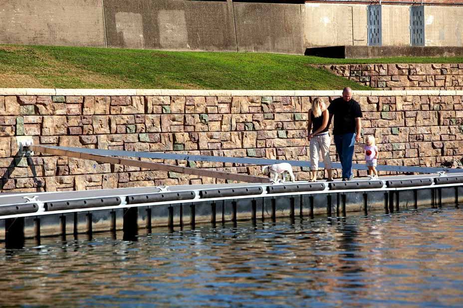 Family with dog walk along doc in front of Ledgetone wall