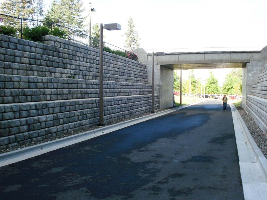 Student walks under overpass and between Cobblestone walls