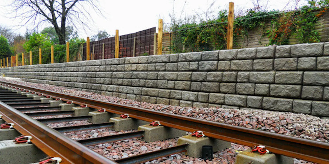 image of cobblestone textured redi-rock wall next to railroad