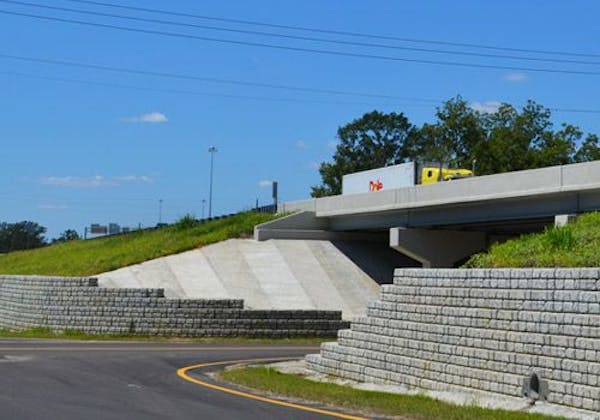 Yellow truck drives on highway supported by Cobblestone retaining walls