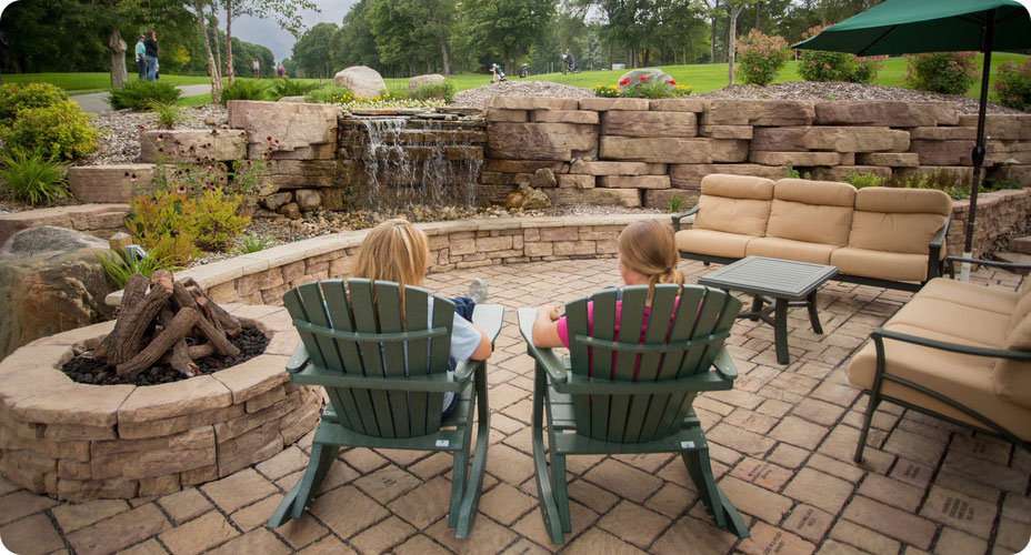 old mission pavers and fire pit and outcropping wall with people in chairs looking at golf course