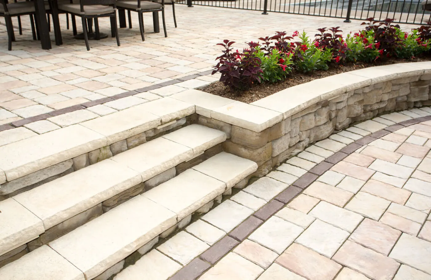 patio area with pavers and dimensional steps and belvedere wall with plants and dimensional coping
