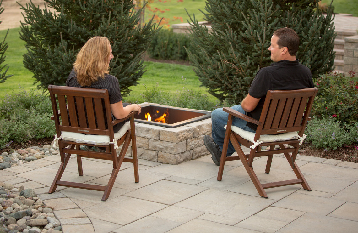 two people sitting next to dimensional fire pit