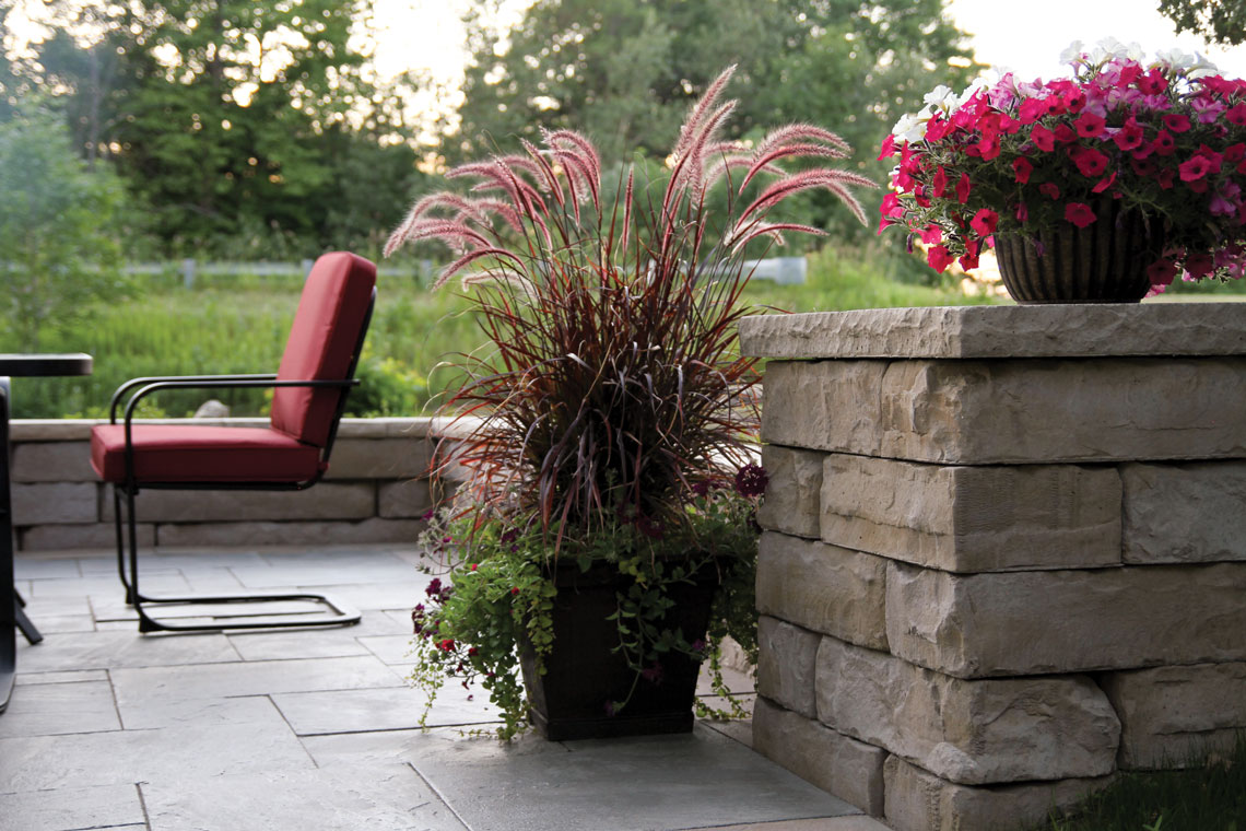 column with cap with flower pot on top in patio area with chairs