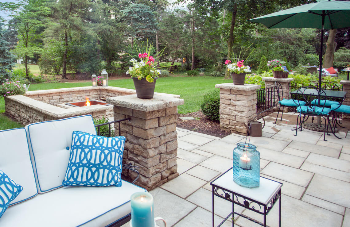patio area with columns and columns caps and pavers and chairs and firepit area