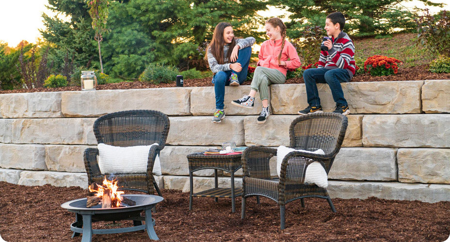 grand ledge wall with kids sitting on top of wall next to fire pit