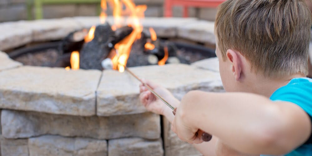 child roasting marshmallow over firepit