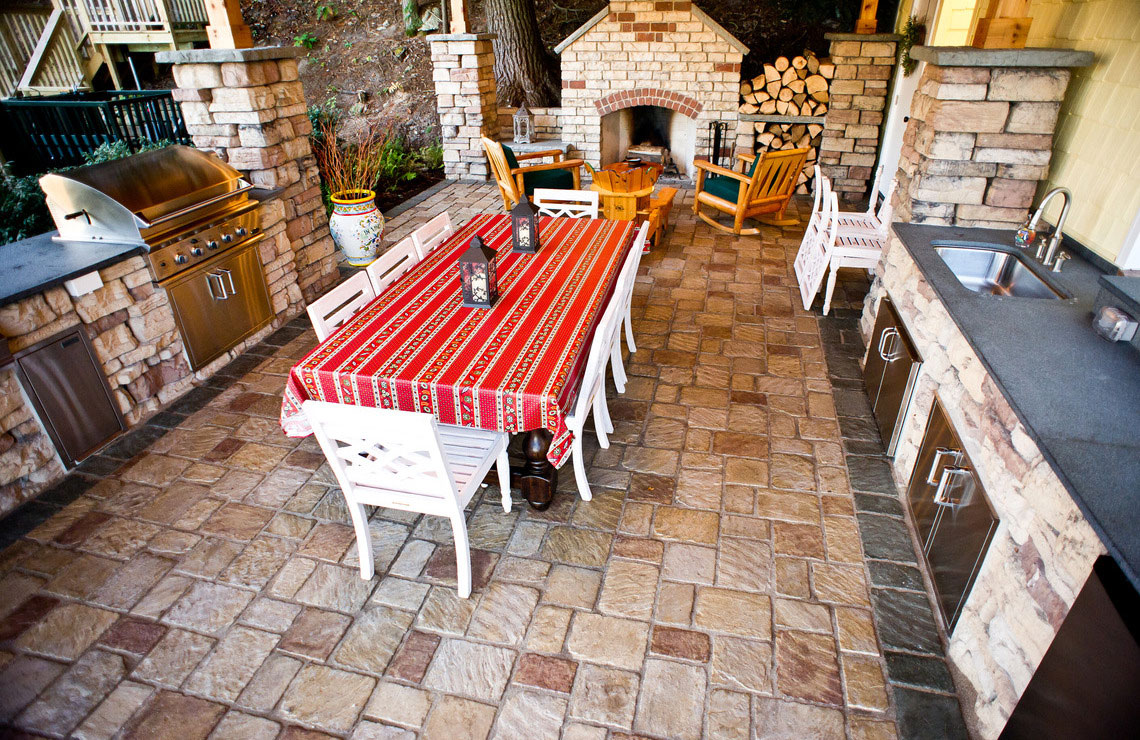 old mission pavers for outdoor kitchen area with a stove, grill, table, chairs, and a counter with sink