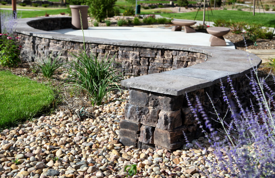 curving belvedere wall with dimensional coping next to lavender flowers 