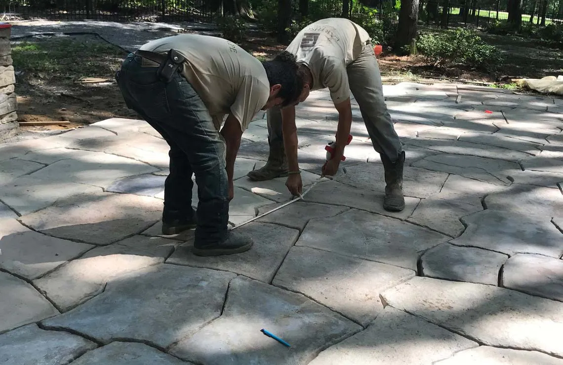 Landscape workers measure and lay Rosetta Hardscapes Grand Flagstone pavers for a Mississippi project.