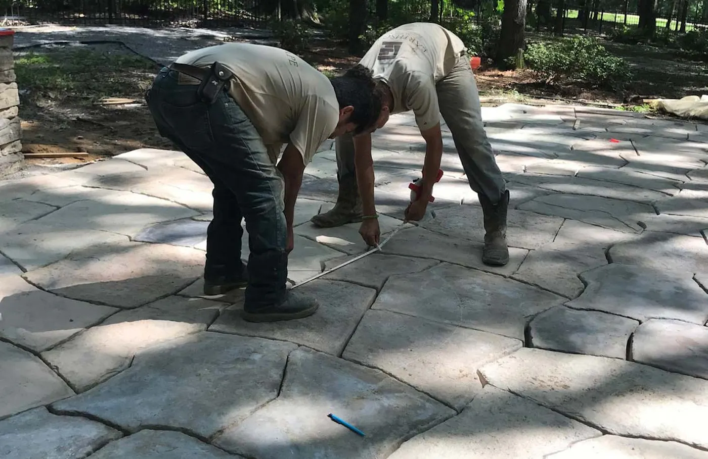 Landscape workers measure and lay Rosetta Hardscapes Grand Flagstone pavers for a Mississippi project.