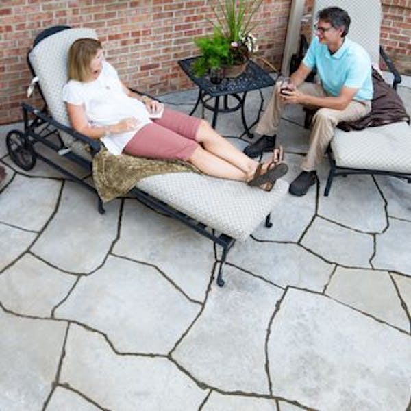 couple sitting on chairs in patio with Grand Flagstone