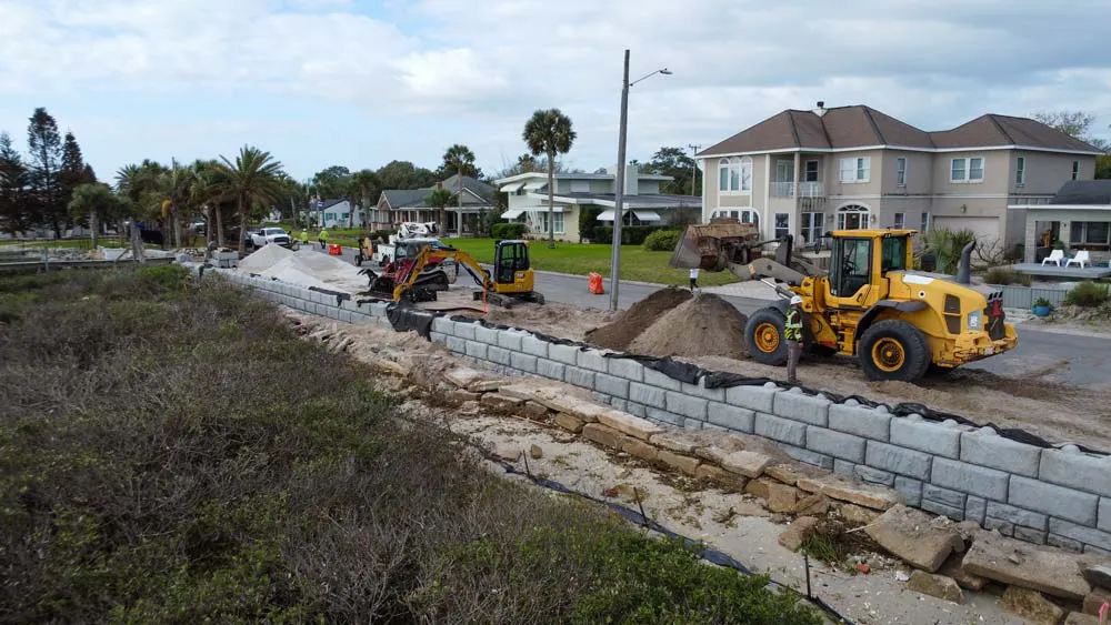 The new Redi-Rock retaining wall is being installed immediately behind the failing existing wall.