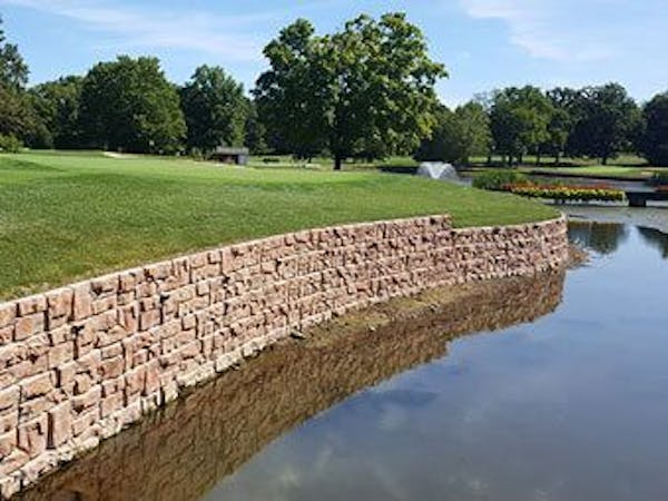 Redi-Rock retaining wall with curves for golf course pond.