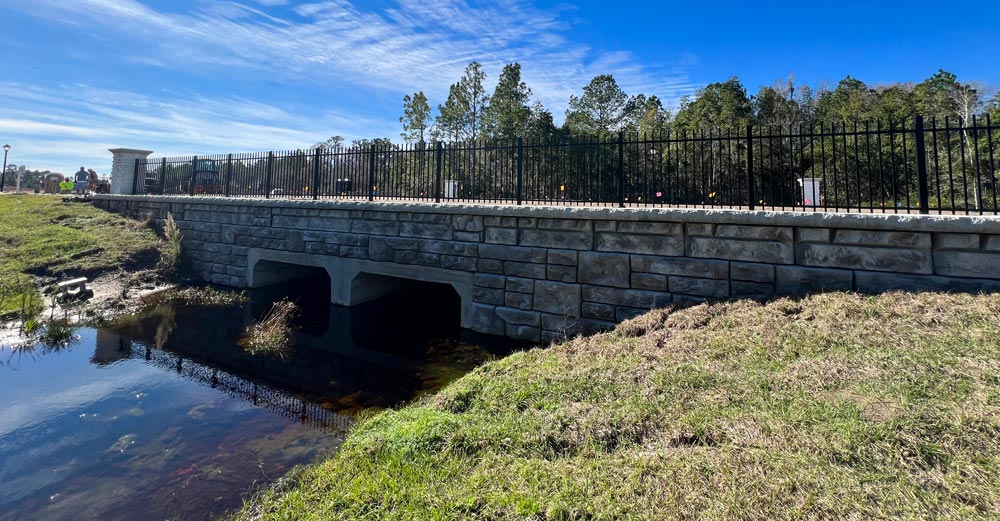 image of finished redi-rock wall for box bridge culvert with blue sky and water under bridge